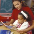 Teacher Reading With Child In Classroom